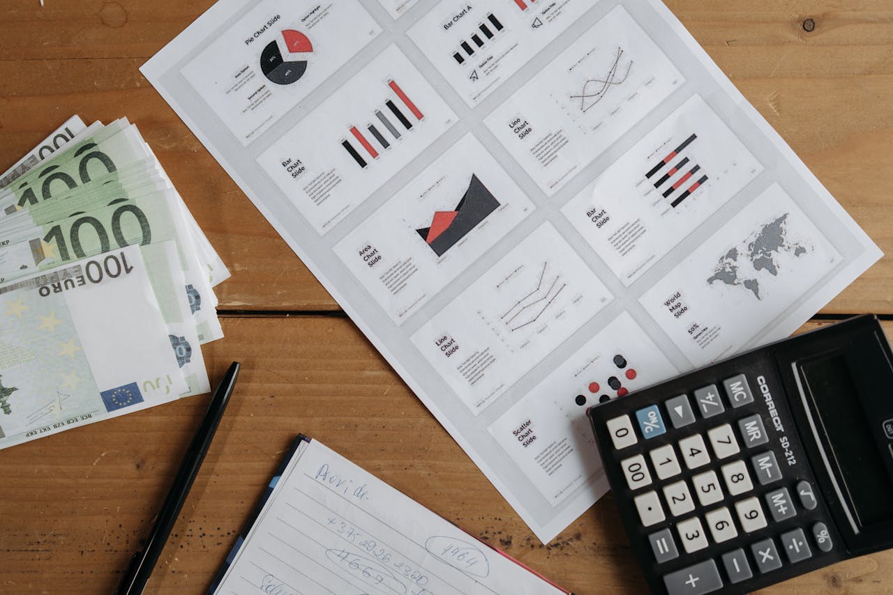services-01 Euro banknotes, graphs, and calculator on a wooden table setup for financial analysis.