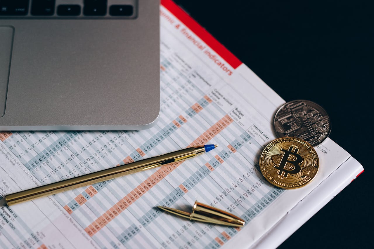 why-choose-us Flat lay of Bitcoin coins on a financial report with a laptop and pen.